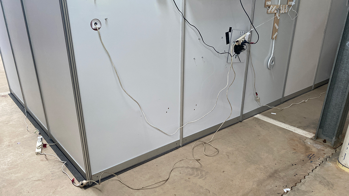  This image shows the back of an information stand at the Alice Springs show. Multiple power boards and extension cords can be seen strung together.
