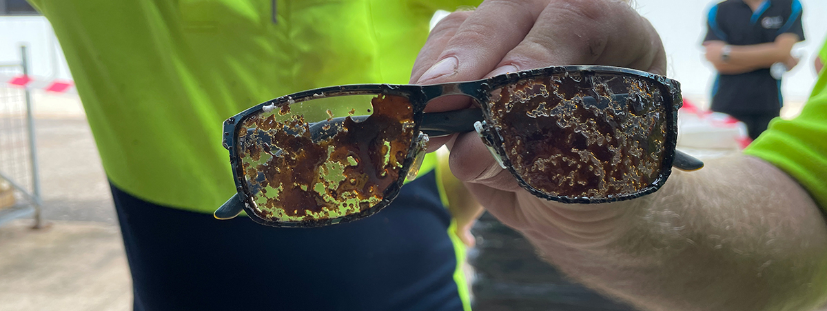 This image shows an unidentified person holding the glasses of the injured worker. The lens of the glasses is covered in melted polystyrene.