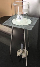 Bunsen burner set up with tripod, gauze mat with ceramic centre and glass beaker.