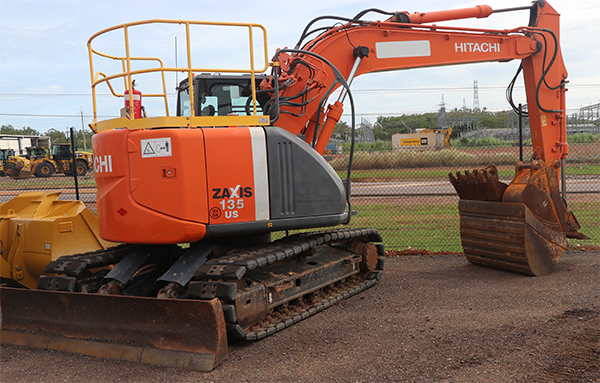 Image shows an excavator in a hire yard with smaller attachments preloaded into the larger bucket. 