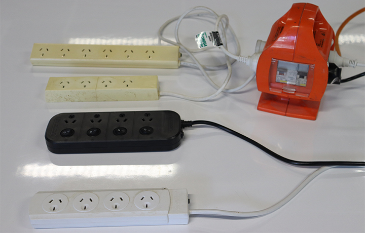 The image shows four domestic power boards plugged into an outlet box, which is the correct way to power multiple power boards.