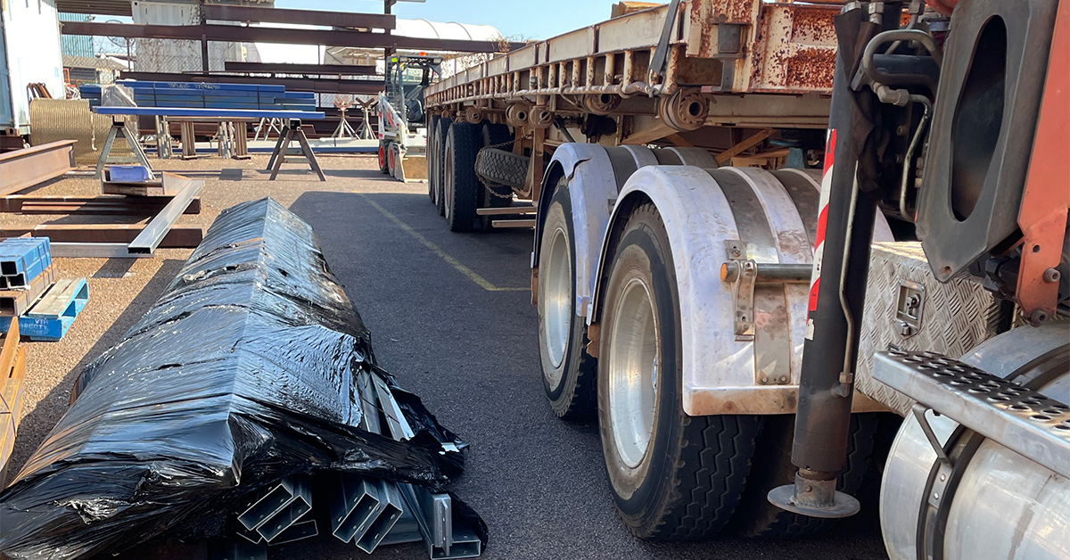 The image shows the incident scene, the side of the trailer is to the right of the image and the bundled steel is on the ground on the left of the image.