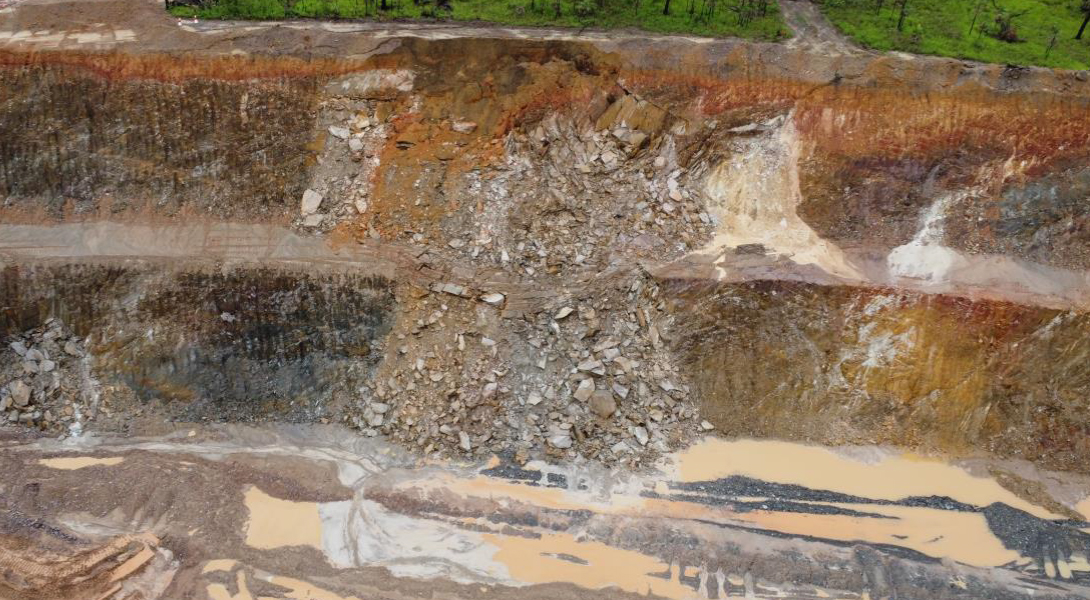 The image is an aerial view showing a mining pit slippage due to wet weather.