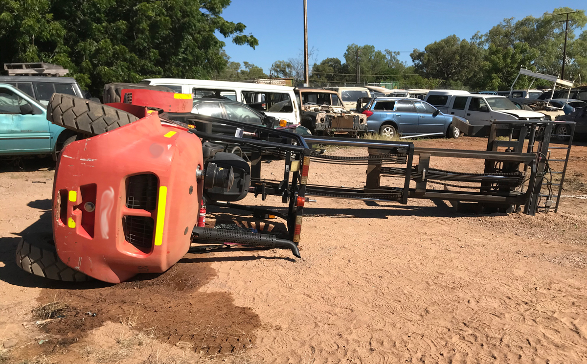Unfortunately this is becoming a familiar sight for WorkSafe Inspectors over the past few weeks. Image shows a forklift on its site in a dirt yard. In the background are a number of car wrecks.