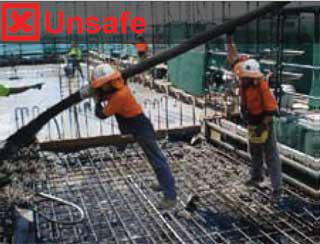 Stretching the delivery hose to each a pour location is unsafe. Image show two construction workers stretching a delivery hose