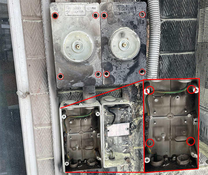 Capping plugs were missing and holes drilled through the back of the isolator at the fire in the Darwin CBD. This image shows four fire damage isolators from a fire in the Darwin CBD. Red circles on the image highlight capping plugs were missing and a insert image shows a close up of the internals of one isolator without its cover showing the back of the isolator had been drilled through.