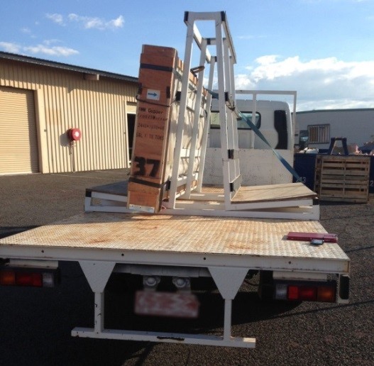 A single set of restraints were used to secure both loads. Rear view of a flat bed truck with A-frame carrying a load